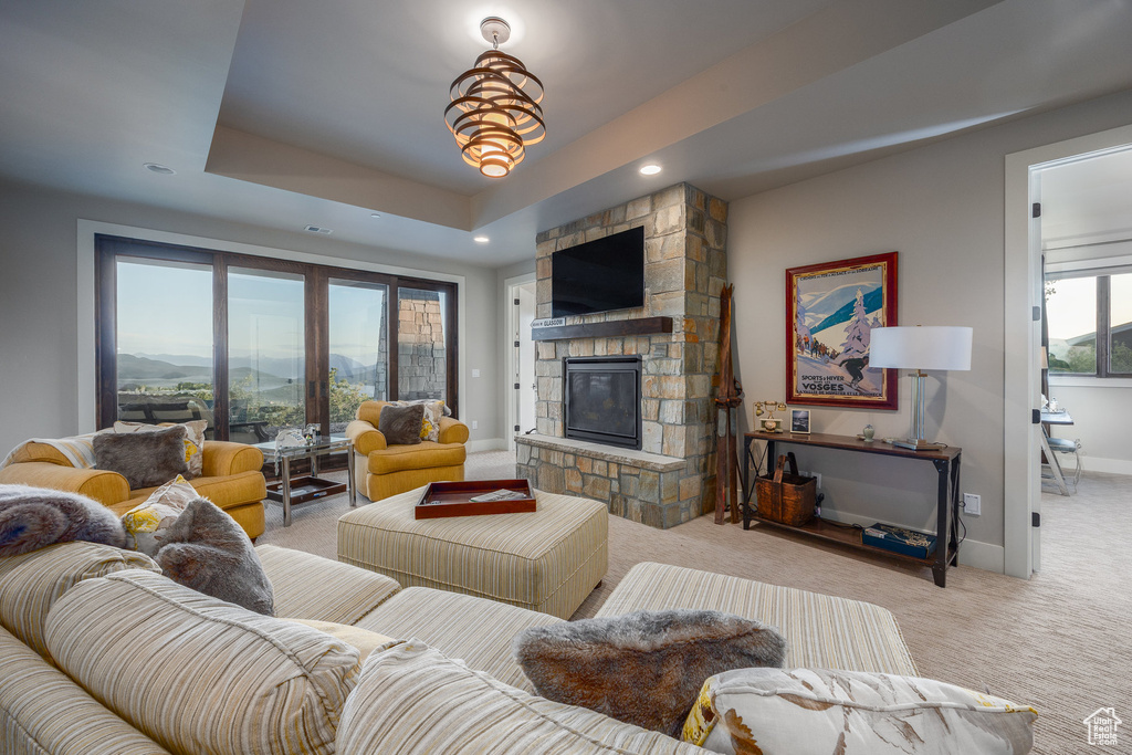 Carpeted living area featuring a fireplace, recessed lighting, baseboards, and a raised ceiling