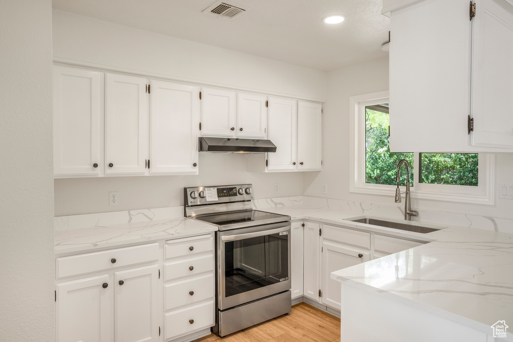 Kitchen with stainless steel electric range oven, a sink, under cabinet range hood, light stone counters, and recessed lighting