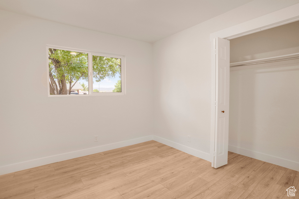Unfurnished bedroom with light wood finished floors, baseboards, and a closet