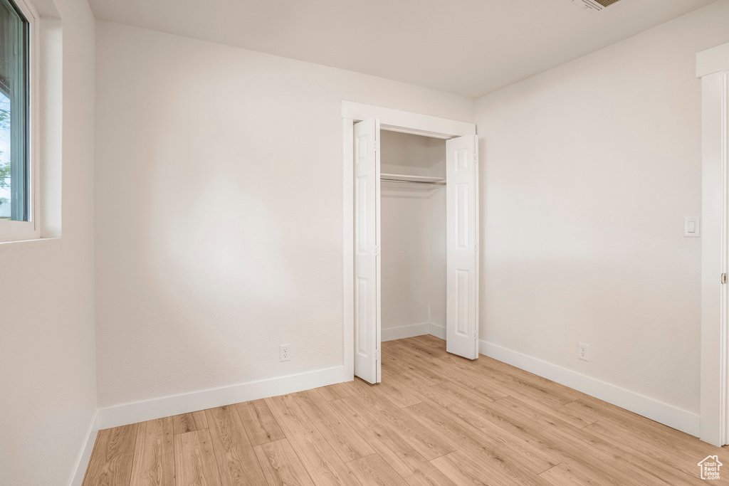 Unfurnished bedroom featuring light wood-style floors, baseboards, and a closet