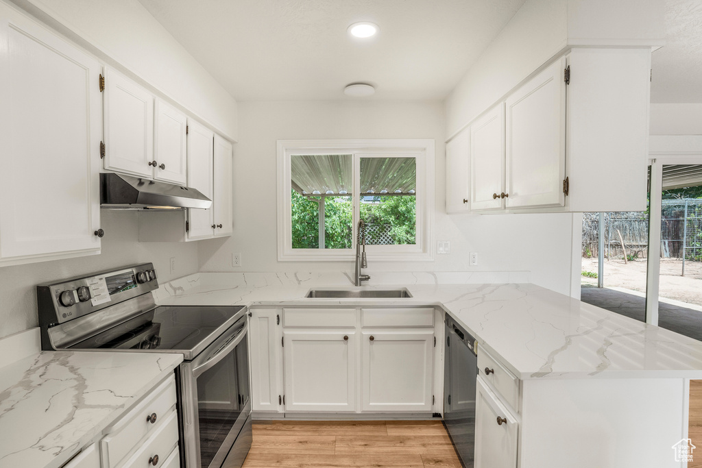 Kitchen with appliances with stainless steel finishes, under cabinet range hood, a sink, a peninsula, and plenty of natural light