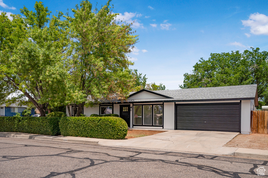 Single story home featuring a garage, driveway, and roof with shingles