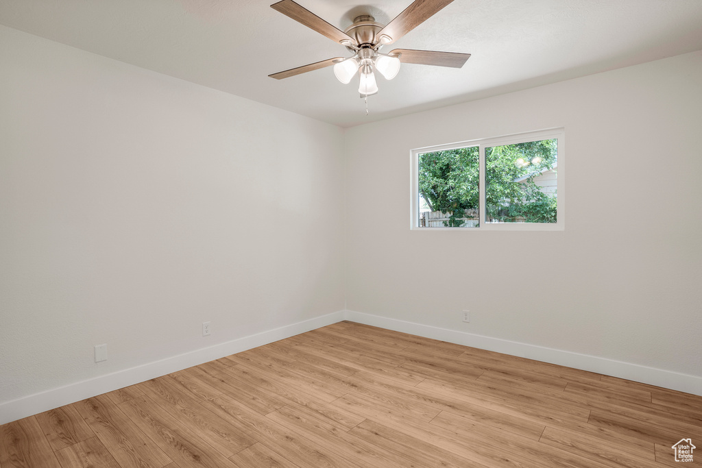 Spare room featuring baseboards, light wood-style floors, and a ceiling fan
