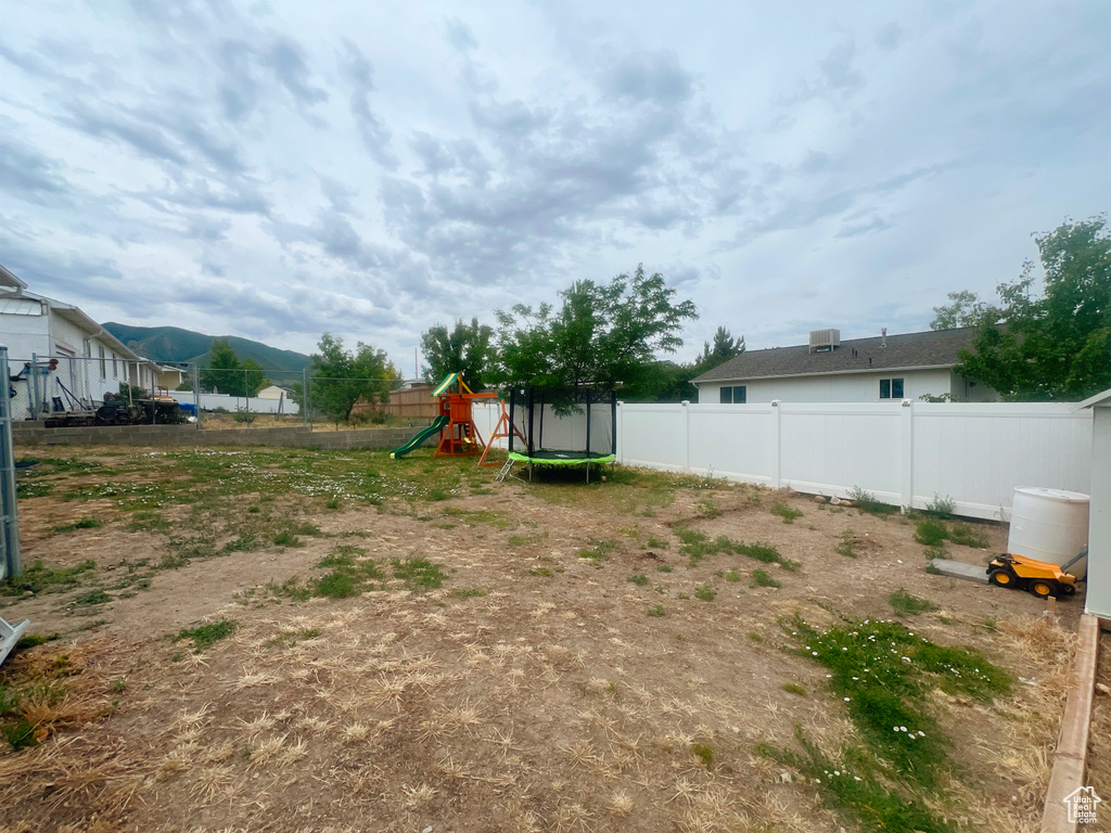 Fenced backyard with a playground and a trampoline