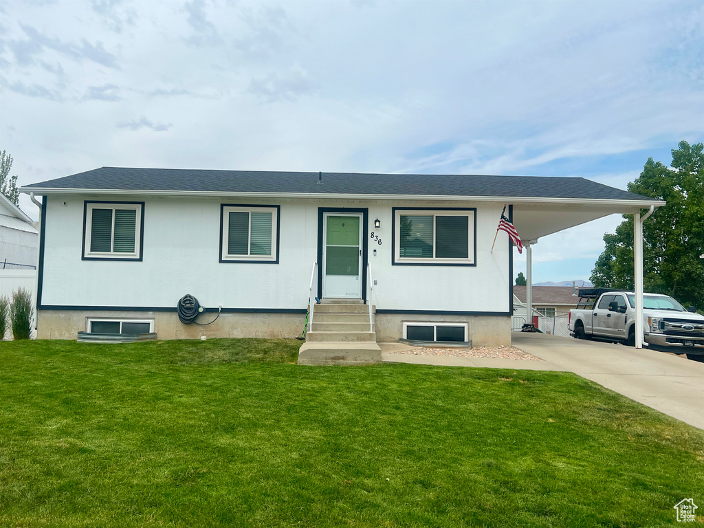 View of front of house featuring entry steps, a front lawn, and driveway