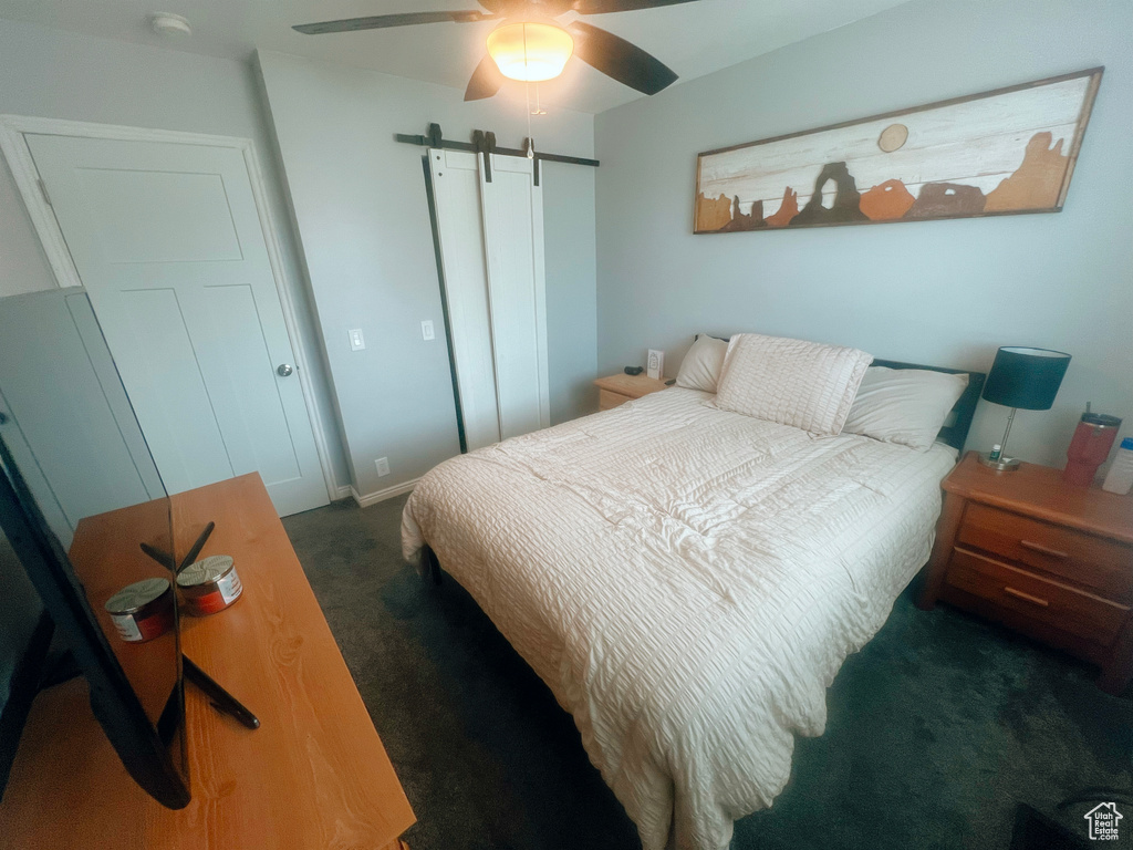 Carpeted bedroom featuring a barn door and ceiling fan