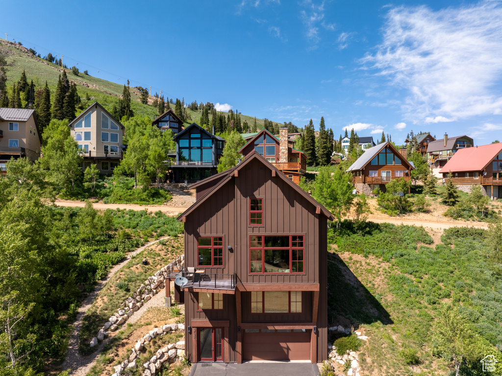 Back of property with a residential view, board and batten siding, an attached garage, and a chimney
