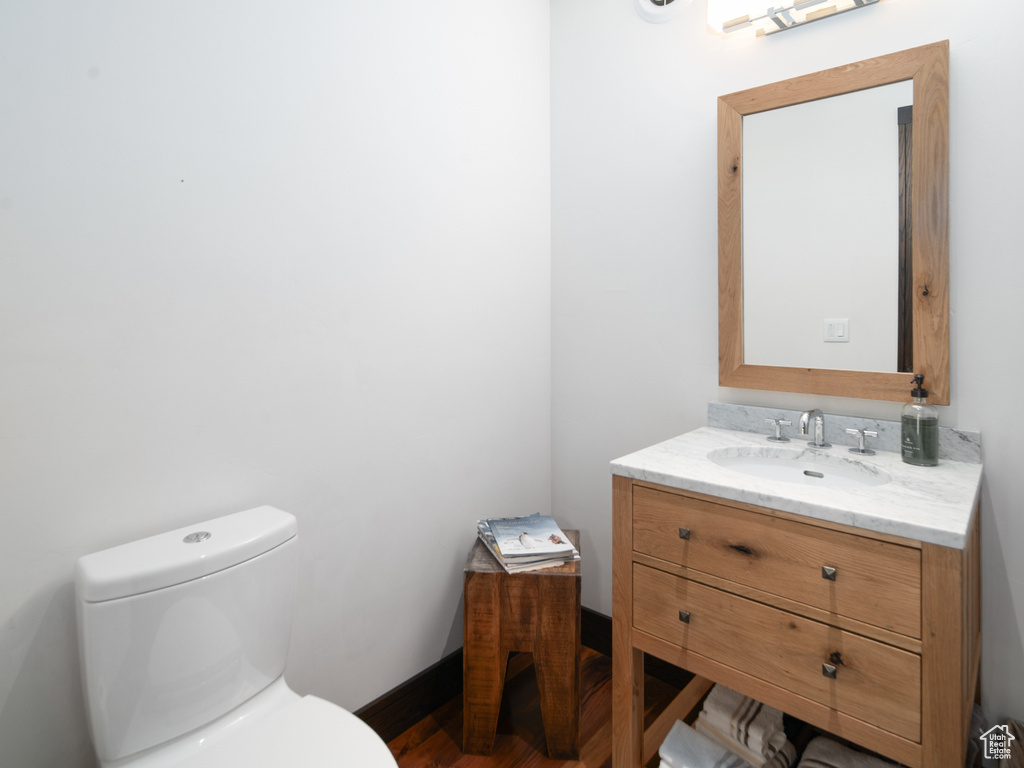 Half bathroom with vanity, toilet, and baseboards