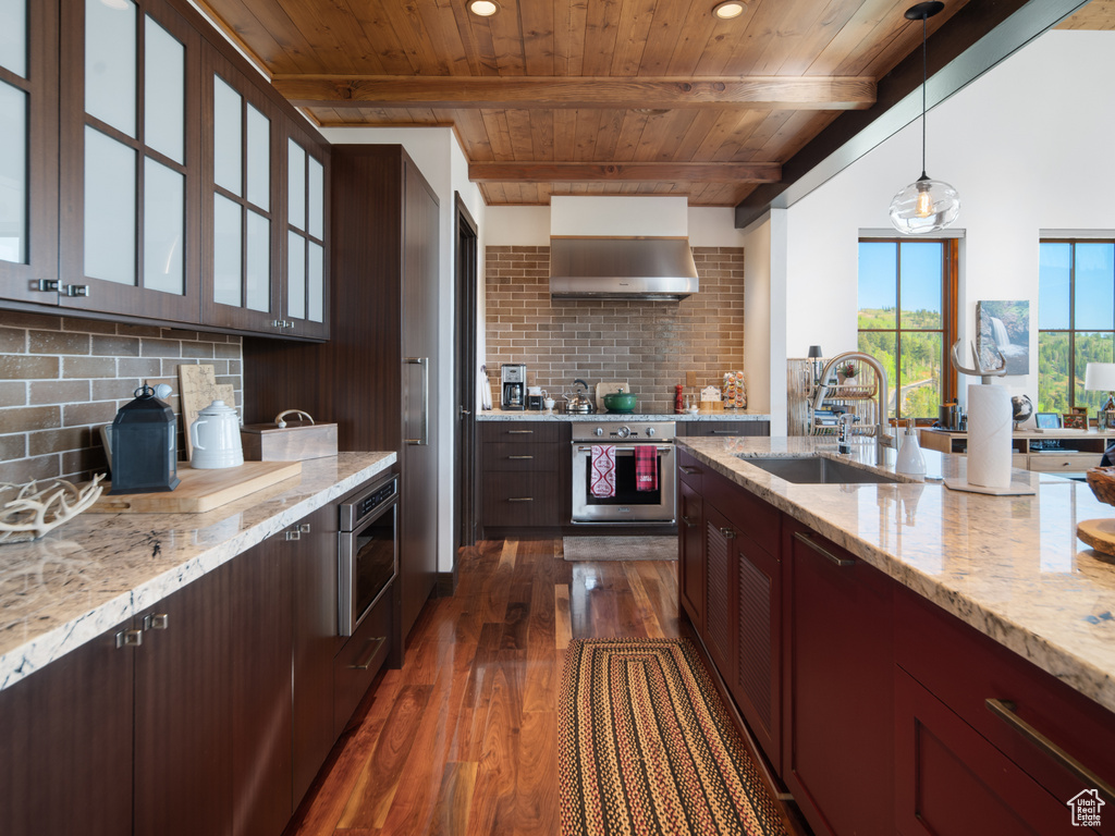 Kitchen featuring oven, wood ceiling with exposed beams, a sink, dark wood-style floors, and tasteful backsplash