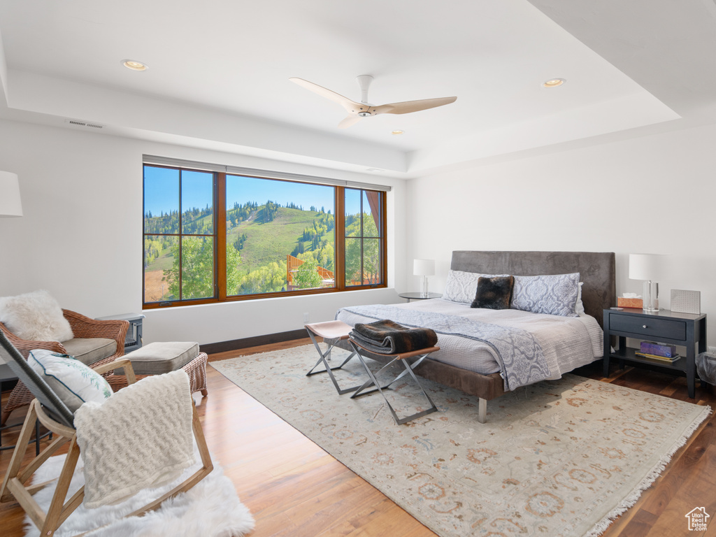 Bedroom with a raised ceiling, wood finished floors, and recessed lighting