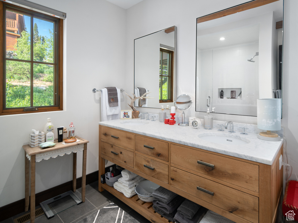 Bathroom featuring double vanity, tile patterned flooring, and a shower