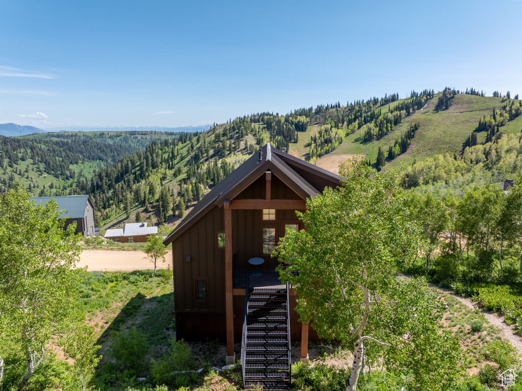 View of front facade with board and batten siding, stairs, a mountain view, and a wooded view