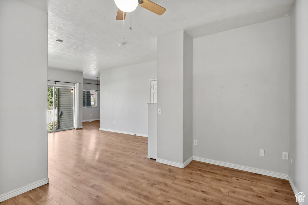 Unfurnished room featuring a ceiling fan, light wood-style flooring, and baseboards