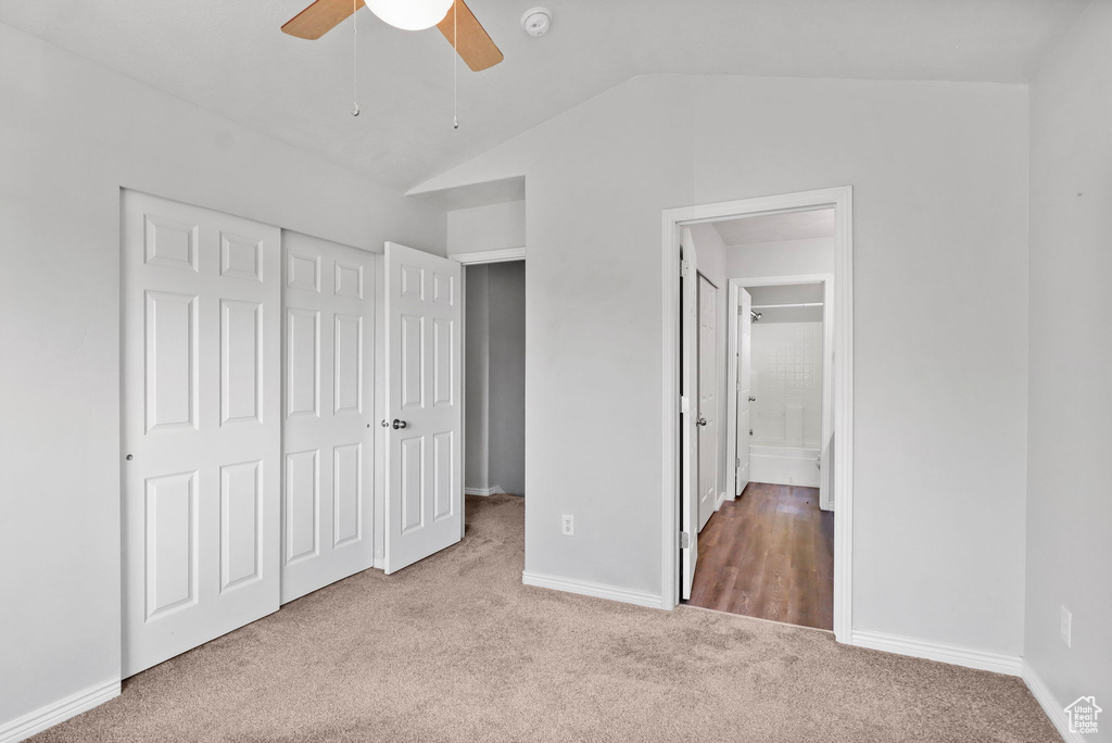 Unfurnished bedroom with carpet flooring, lofted ceiling, a closet, baseboards, and ceiling fan