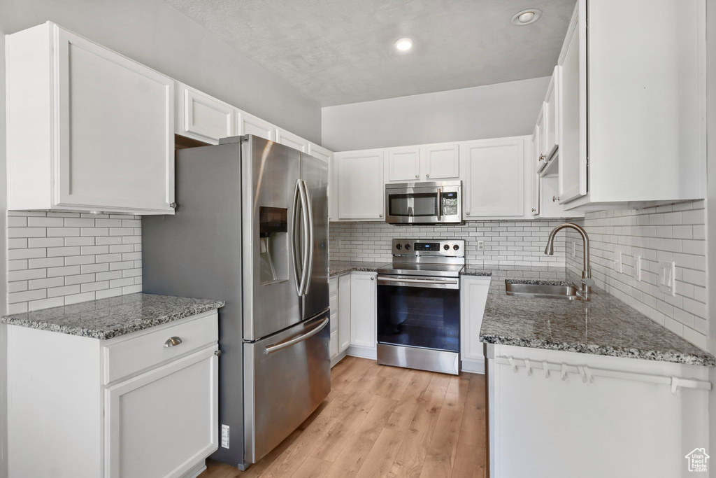 Kitchen featuring stainless steel appliances, a sink, stone countertops, tasteful backsplash, and recessed lighting