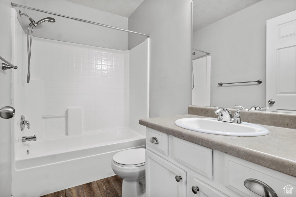 Bathroom with vanity, shower / bath combination, toilet, and wood finished floors