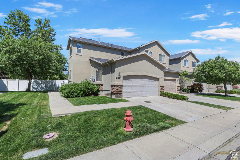 View of front facade featuring stucco siding, stone siding, driveway, and a garage