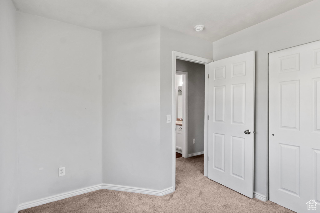 Unfurnished bedroom with light colored carpet and baseboards