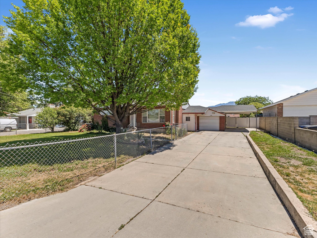 View of front facade featuring concrete driveway, a carport, brick siding, and a garage