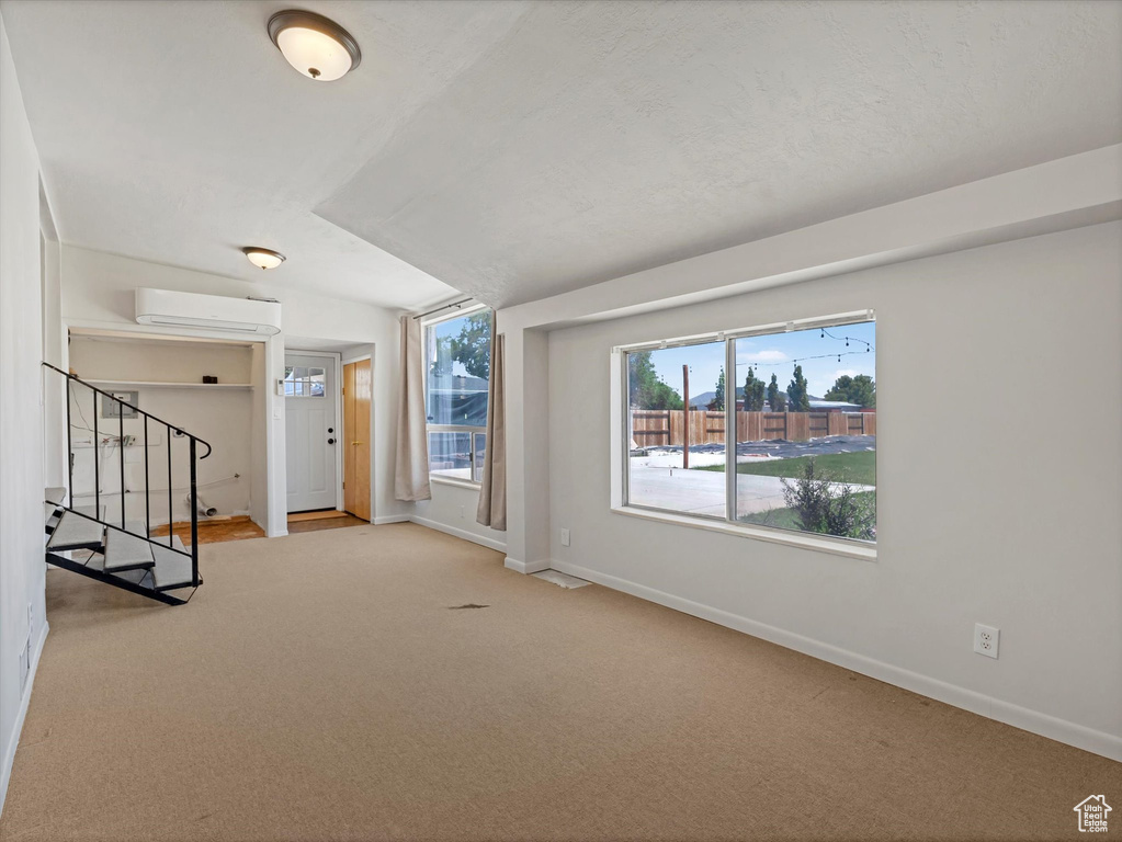 Carpeted foyer with baseboards, stairway, and a wall mounted air conditioner