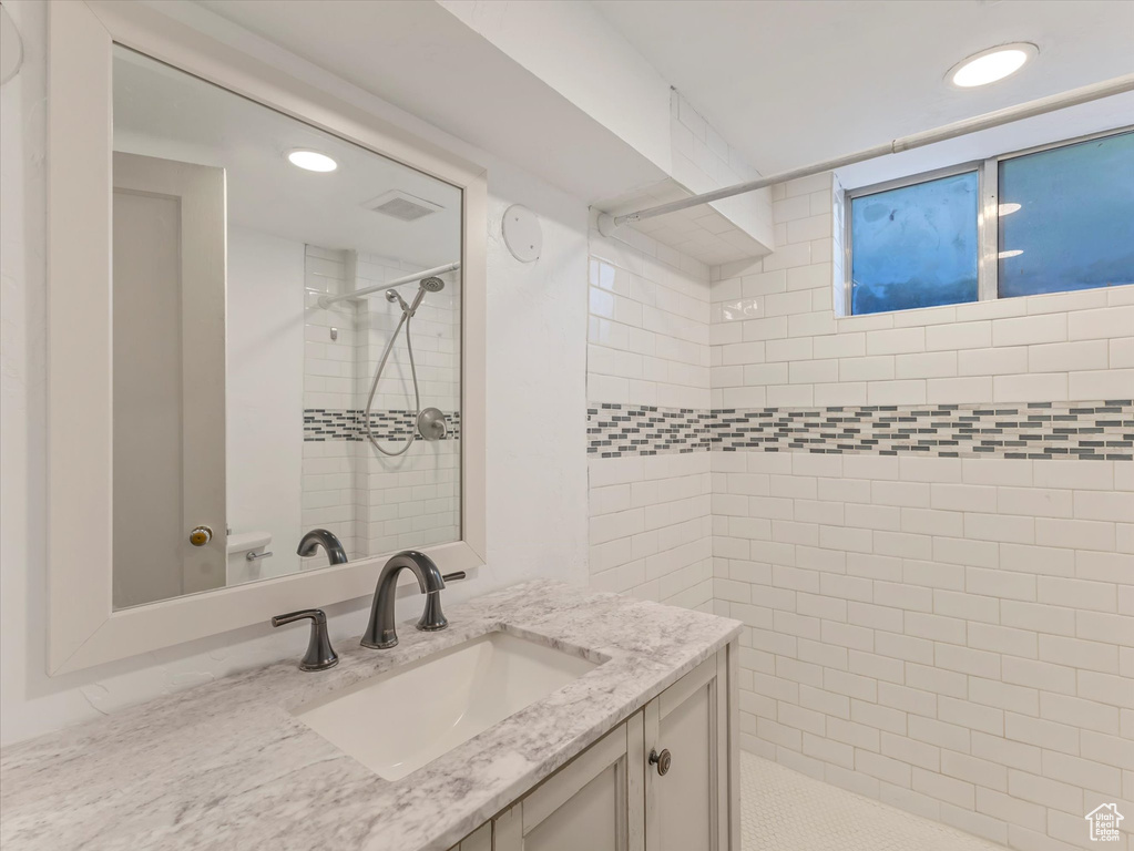 Bathroom with a tile shower, vanity, recessed lighting, and toilet