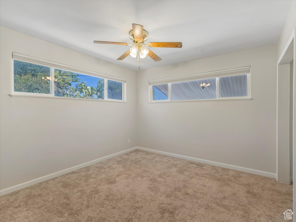 Empty room featuring carpet, baseboards, and a ceiling fan