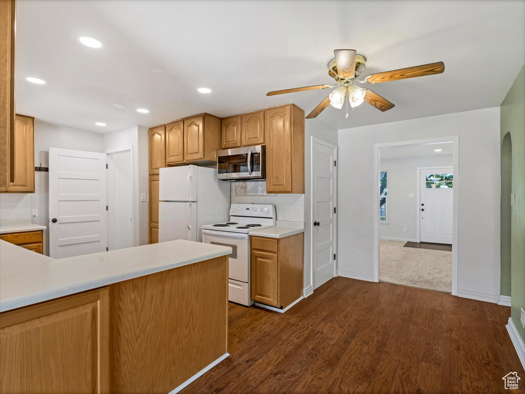 Kitchen featuring white appliances, a ceiling fan, light countertops, baseboards, and dark wood-type flooring