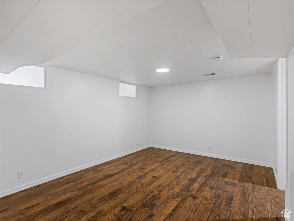 Below grade area with dark wood-type flooring, baseboards, and a drop ceiling