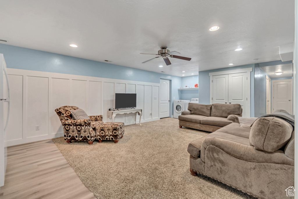 Living room featuring a ceiling fan, washing machine and dryer, a decorative wall, recessed lighting, and light wood-style floors