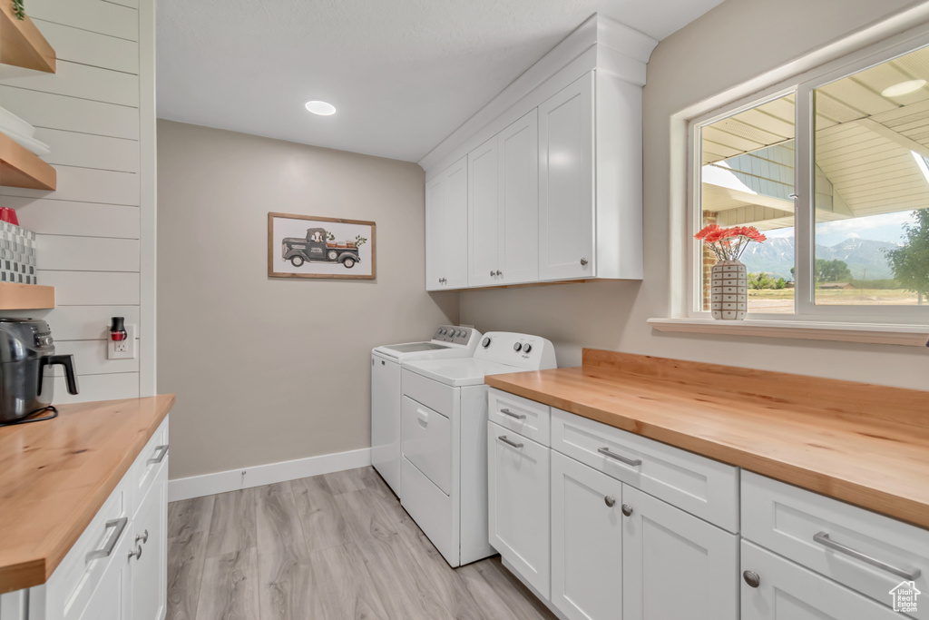 Washroom with washer and dryer, cabinet space, baseboards, light wood-style flooring, and recessed lighting