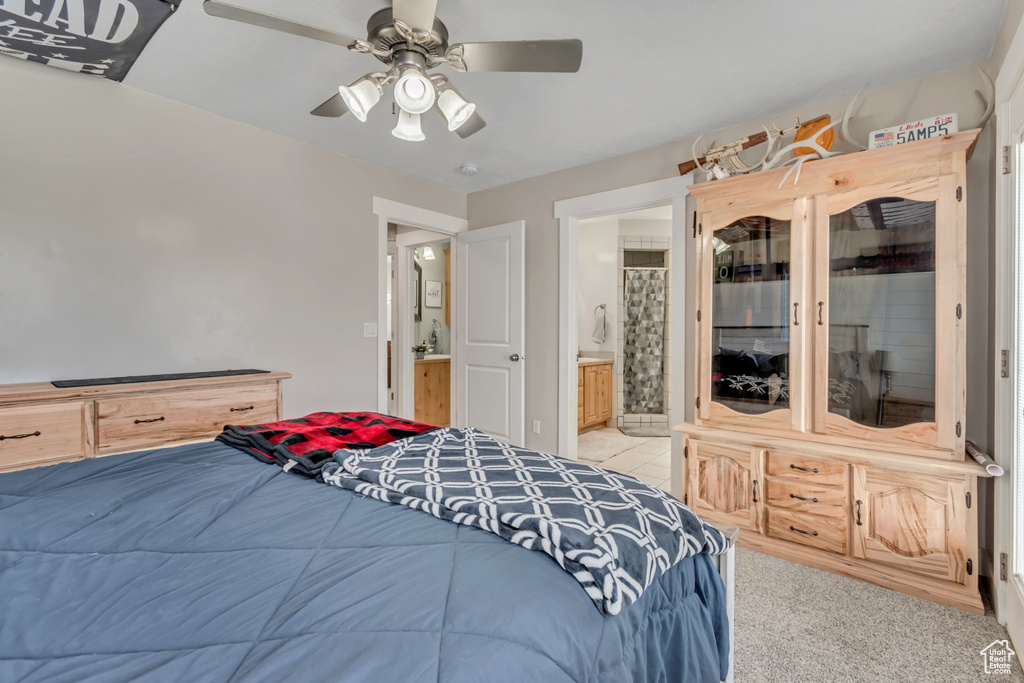 Bedroom with ensuite bathroom, ceiling fan, and light colored carpet