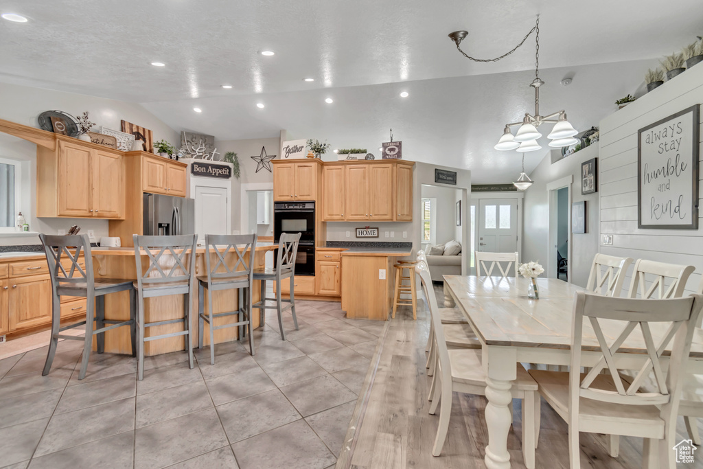 Dining space with recessed lighting, light tile patterned flooring, lofted ceiling, and a chandelier