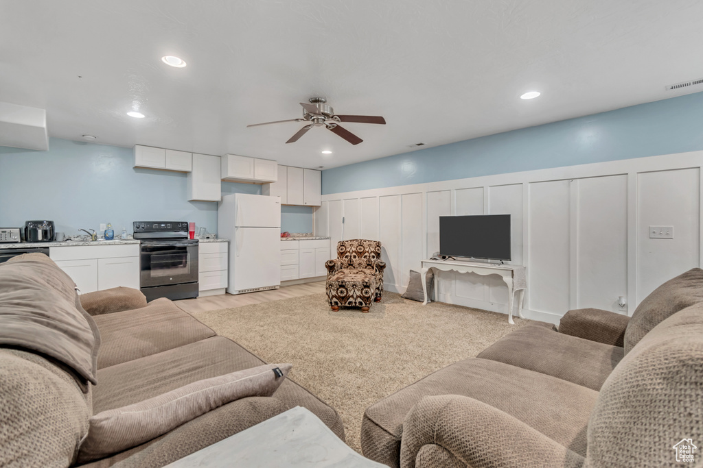 Living area with a decorative wall, ceiling fan, recessed lighting, and wainscoting