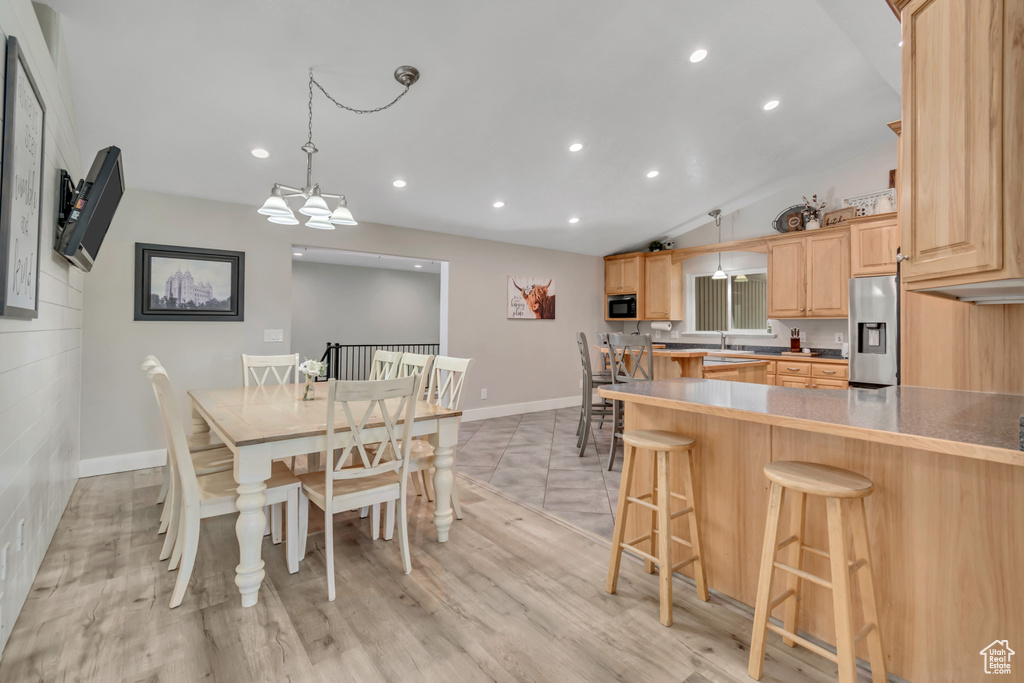 Dining room with recessed lighting, baseboards, lofted ceiling, and light wood-style flooring