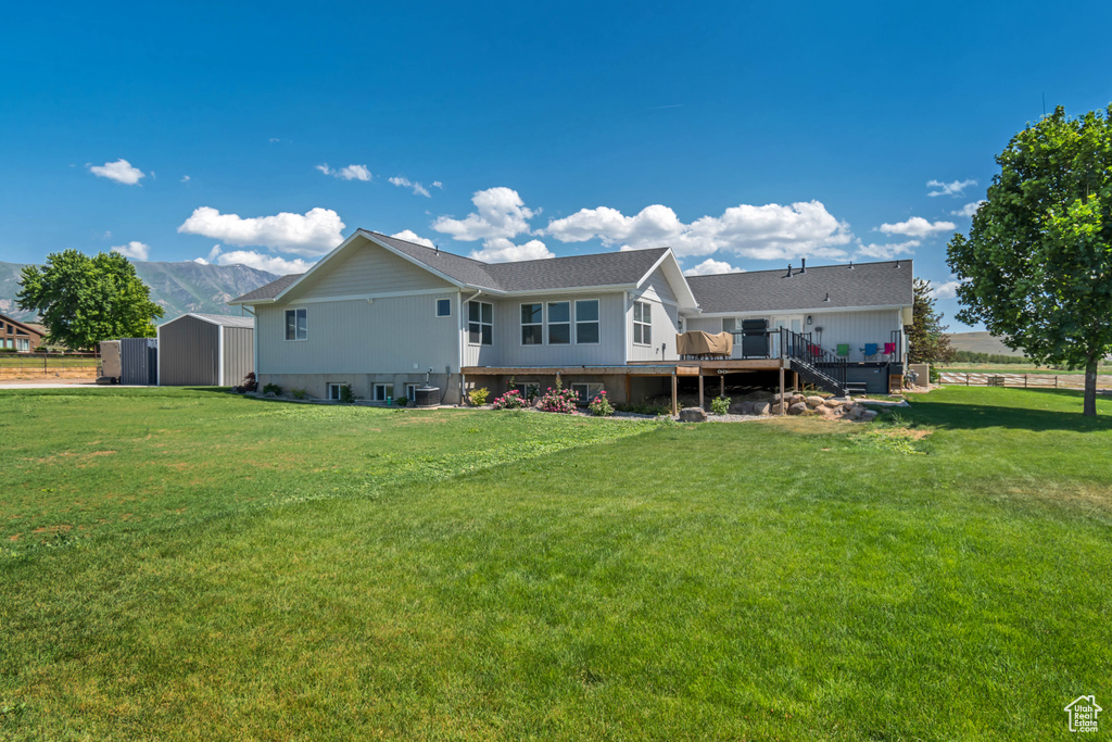 Rear view of house featuring a wooden deck, a yard, and stairway