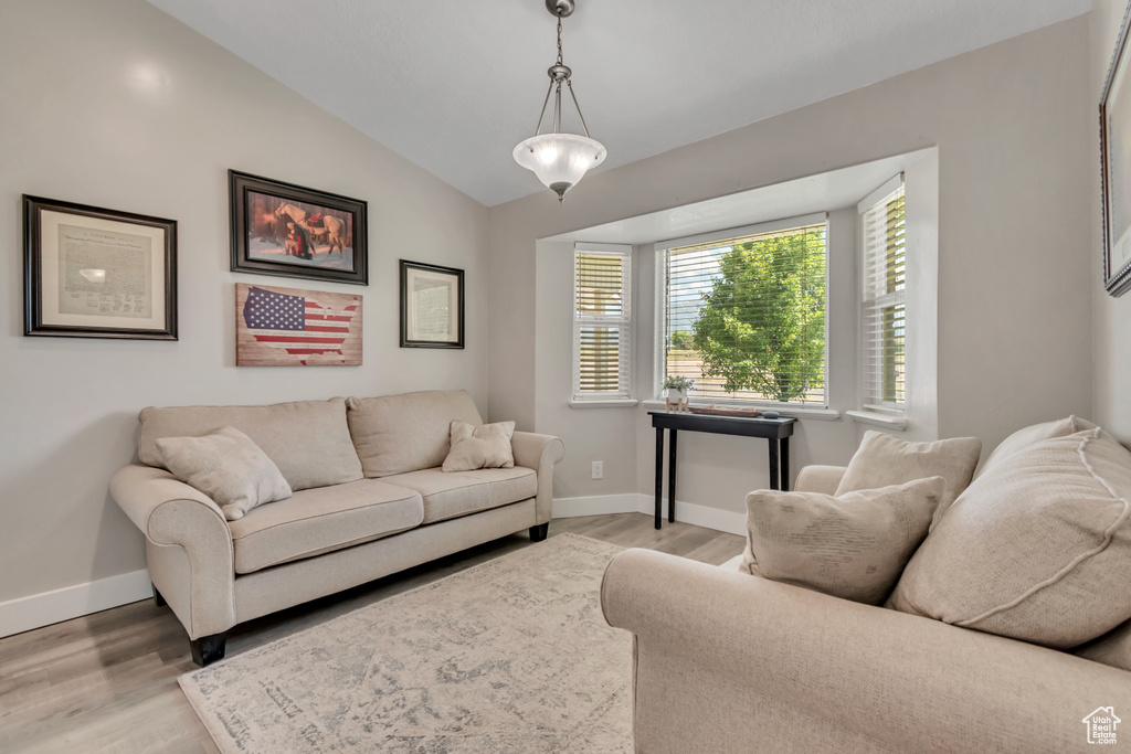 Living room featuring light wood-style floors, baseboards, and lofted ceiling