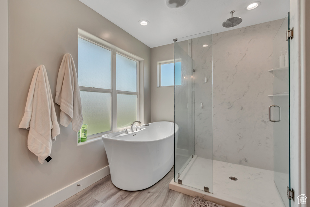 Bathroom featuring a marble finish shower, baseboards, a freestanding bath, wood finished floors, and recessed lighting