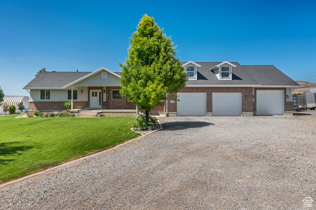 View of front of house featuring brick siding, a porch, gravel driveway, and a front yard