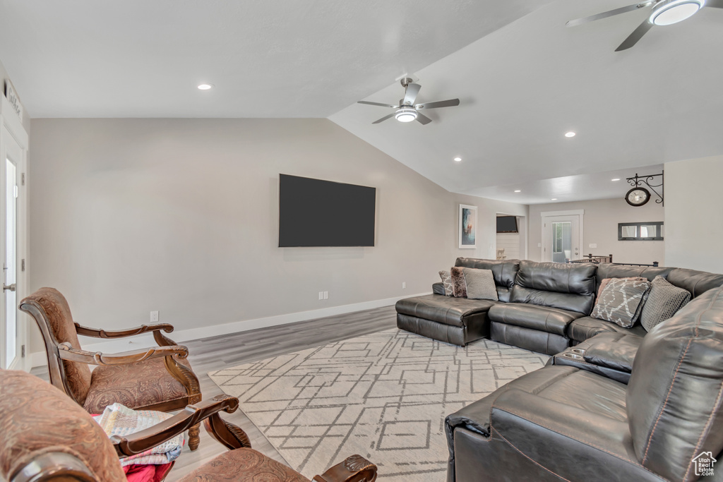 Living room with a ceiling fan, wood finished floors, vaulted ceiling, baseboards, and recessed lighting