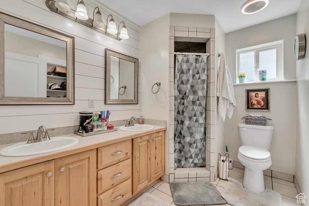 Bathroom featuring a stall shower, double vanity, tile patterned flooring, and toilet