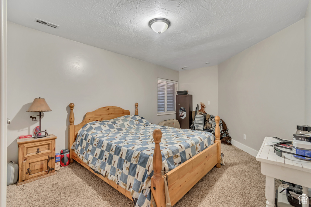 Carpeted bedroom featuring baseboards and a textured ceiling