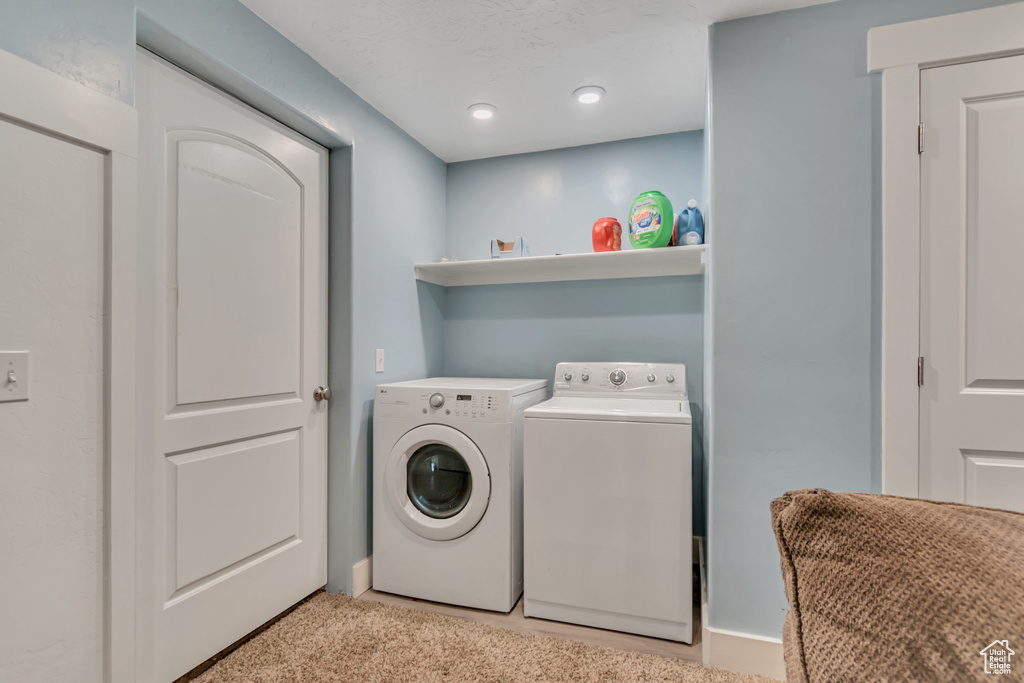 Laundry room featuring washing machine and clothes dryer and light colored carpet