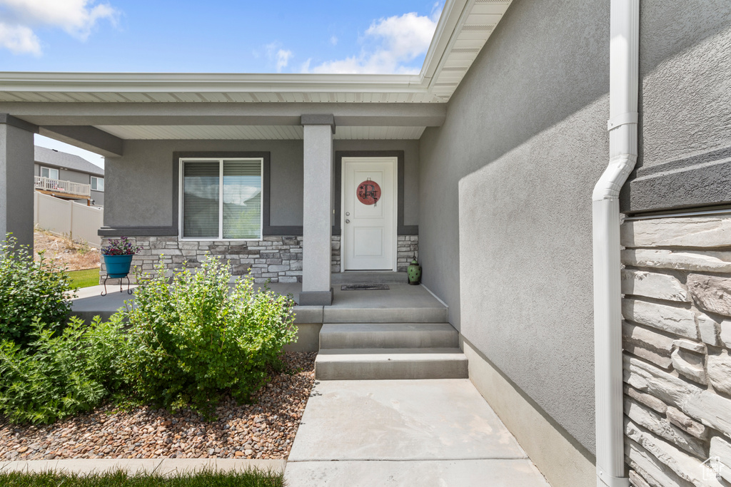 Property entrance featuring stone siding, stucco siding, and covered porch