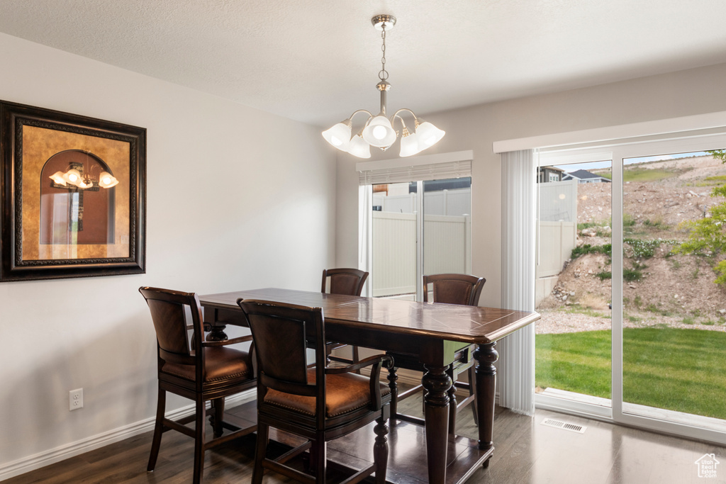 Dining room featuring a chandelier, dark wood-style flooring, and baseboards