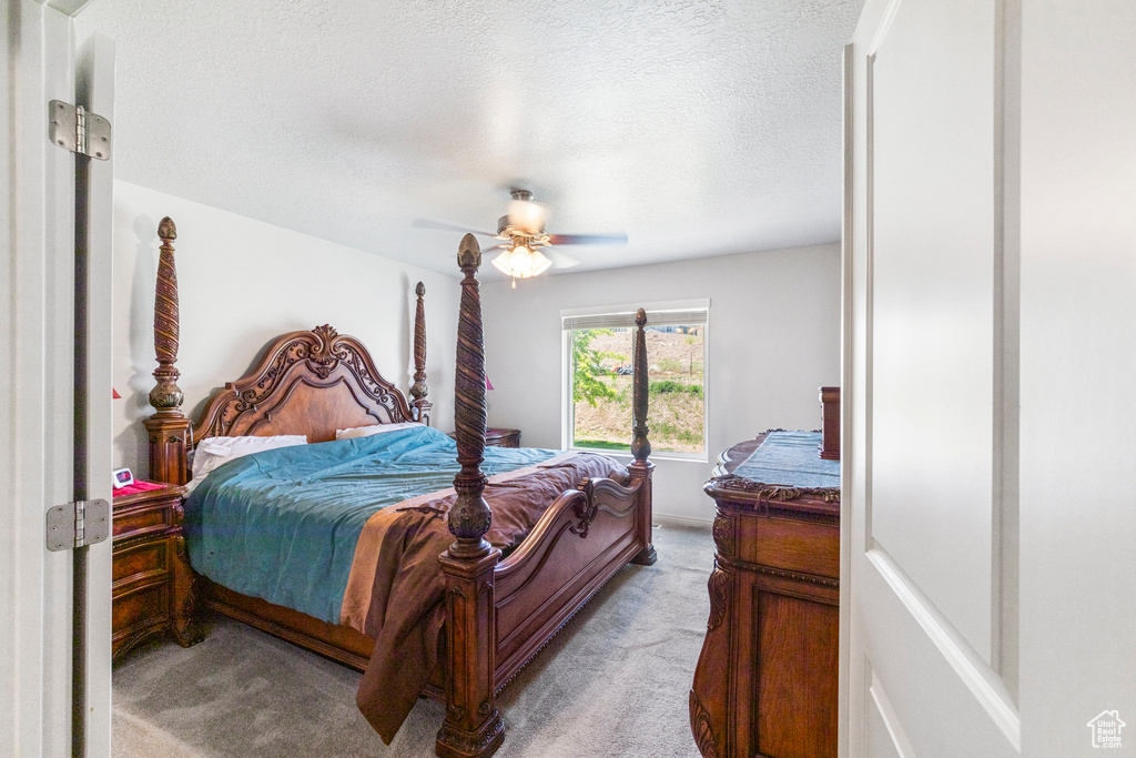 Bedroom featuring light carpet, a textured ceiling, and ceiling fan