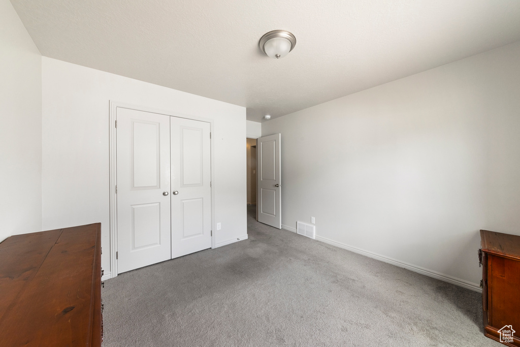 Unfurnished bedroom featuring carpet, a closet, and baseboards