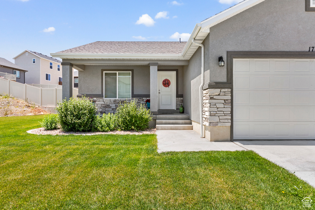View of front of property featuring stone siding, stucco siding, a front lawn, and a garage