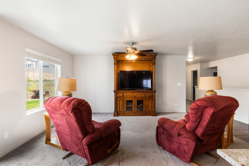 Carpeted living room with ceiling fan and baseboards