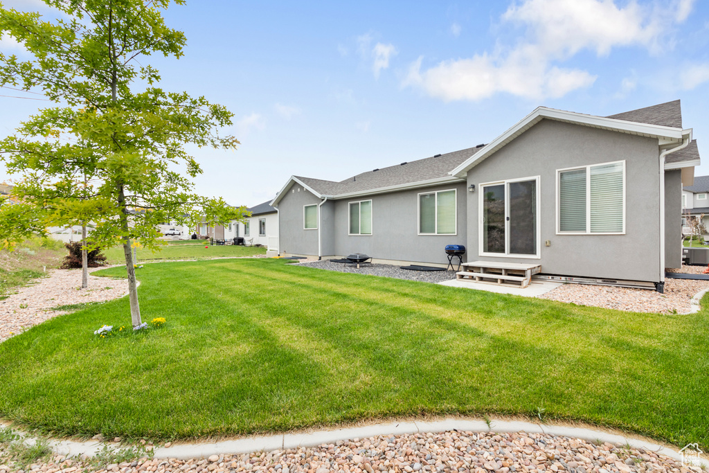 Rear view of property with entry steps, a yard, stucco siding, and a shingled roof