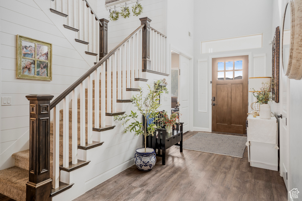 Foyer with dark wood-type flooring, stairs, a towering ceiling, and baseboards